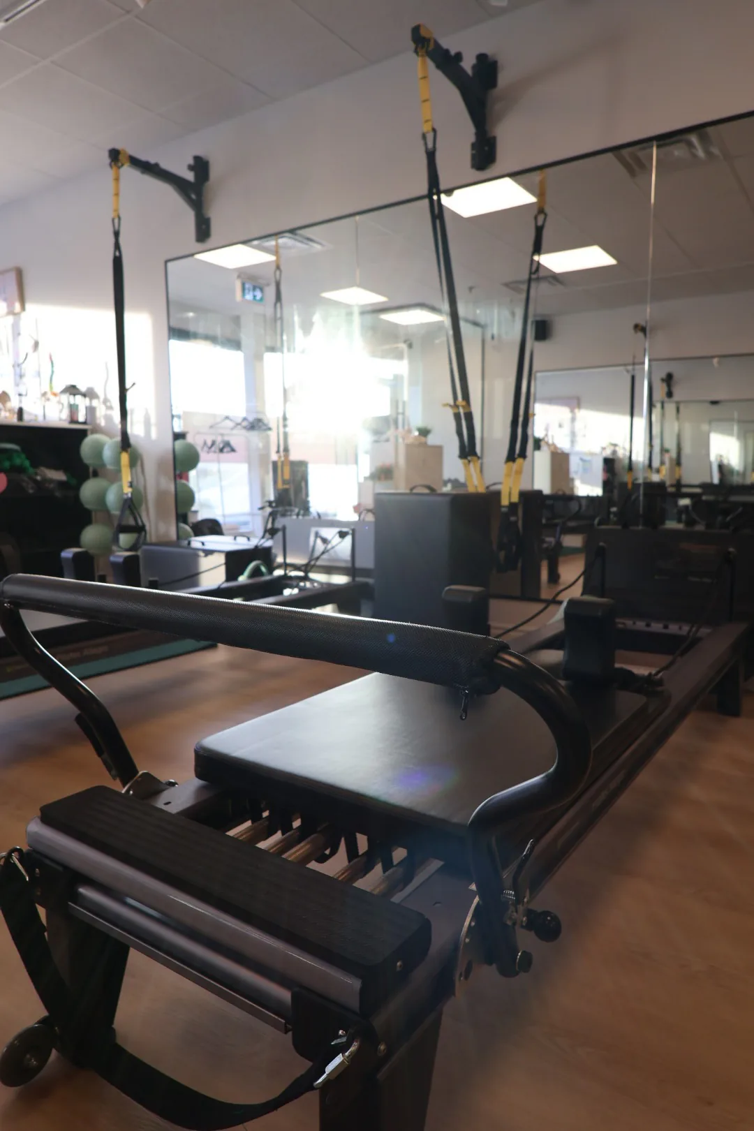Pilates reformer and tower in the sunlit first studio room.
